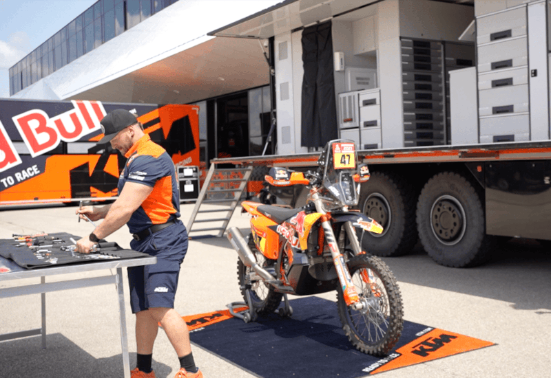 Ein KTM-Techniker arbeitet mit Werkzeug an einem Rennmotorrad aus einem mobilen Lager – unterstützt durch Ontego, SAP und offline nutzbare Lösungen.